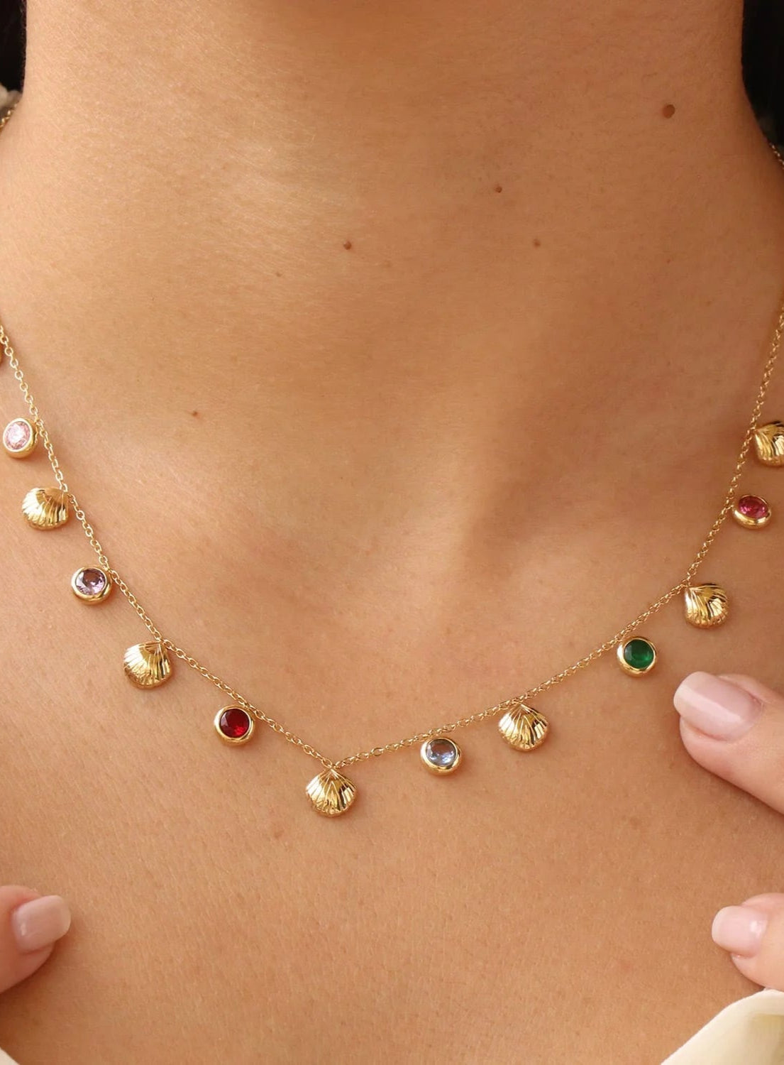 Gold necklace with colorful gemstones worn by a person