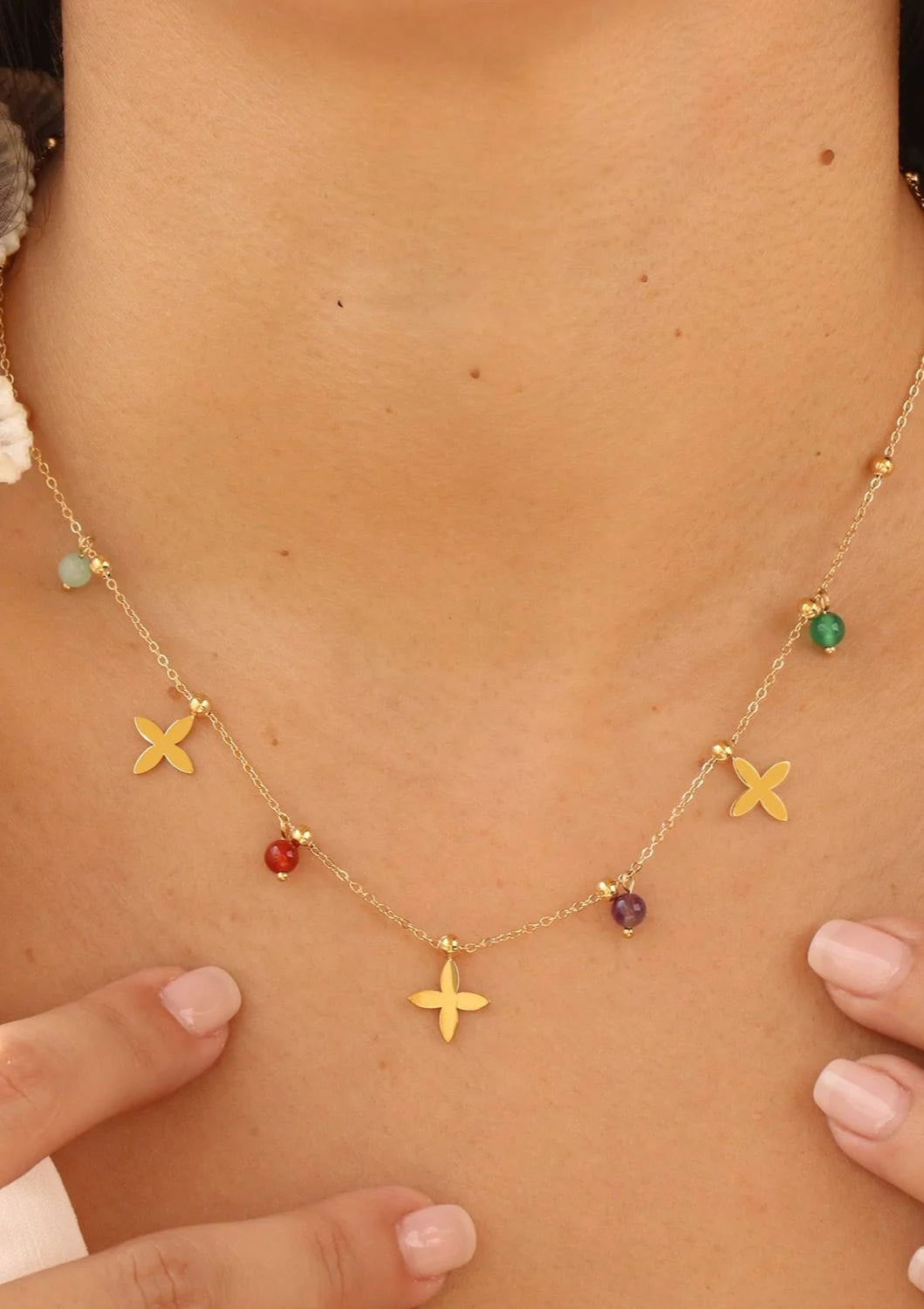 Necklace with colorful beads and gold 'X' charms on a person's neck