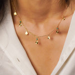 Gold necklace with small pendants on a person wearing a white shirt