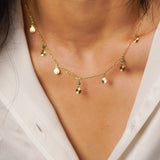 Gold necklace with small pendants on a person wearing a white shirt