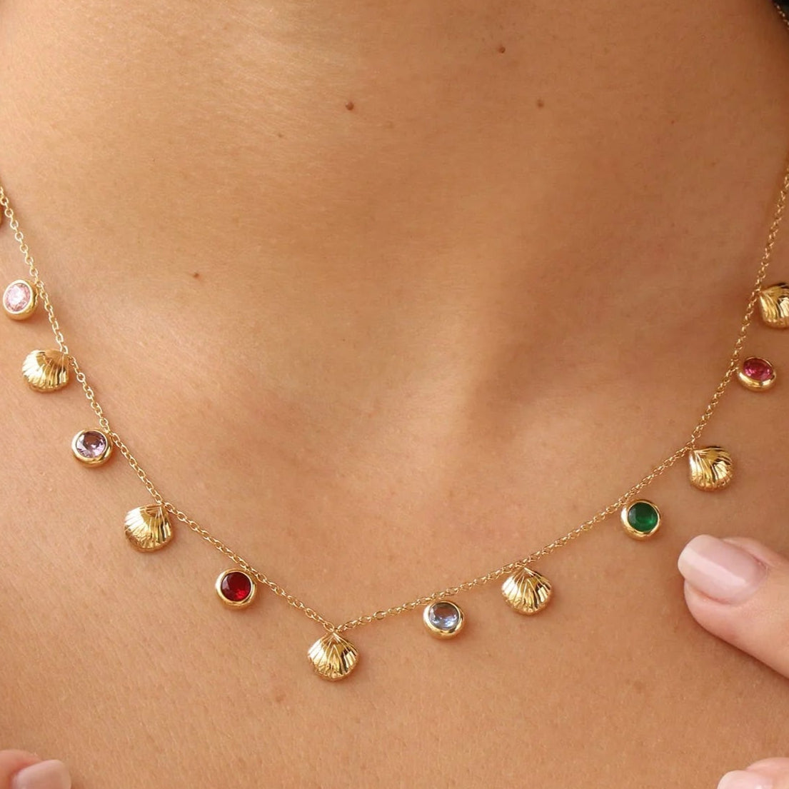 Gold necklace with colorful gemstones worn by a person