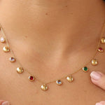 Gold necklace with colorful gemstones worn by a person
