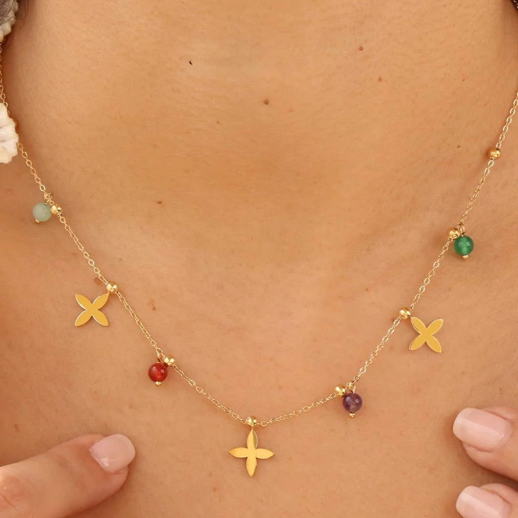 Necklace with colorful beads and gold 'X' charms on a person's neck